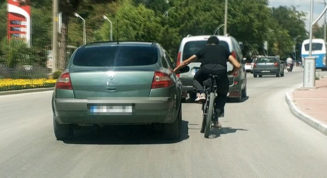 Otomobil kapısına tutunan bisikletli sürücüyle sohbet etti
